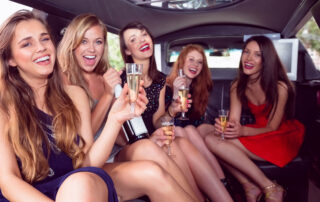 Happy friends drinking champagne in LuxuryRide Black car service on a night out